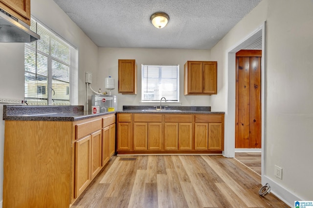 kitchen with a textured ceiling, light wood-type flooring, and sink