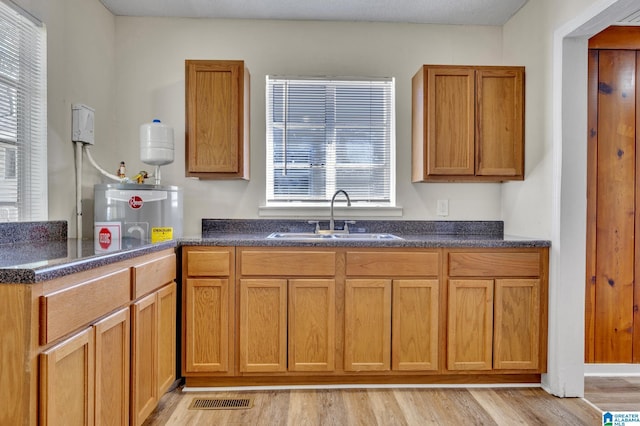 kitchen with light hardwood / wood-style floors, sink, and water heater