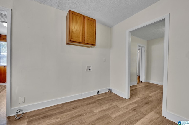 clothes washing area with washer hookup, a textured ceiling, and light hardwood / wood-style floors