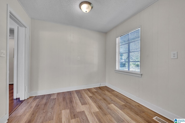 unfurnished room featuring light wood-type flooring and a textured ceiling