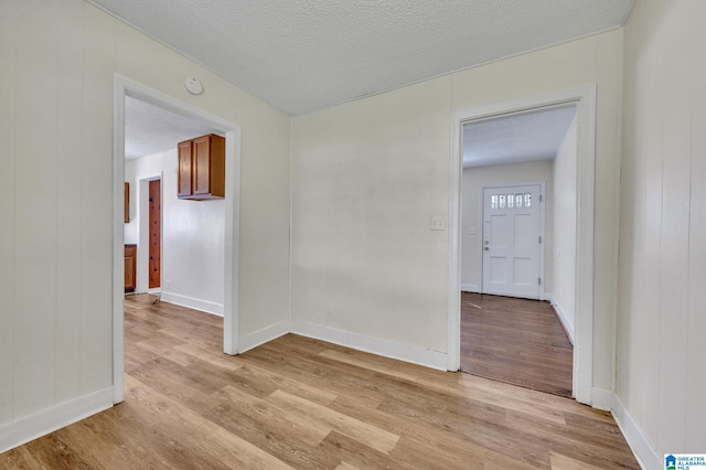 empty room with light wood-type flooring and a textured ceiling