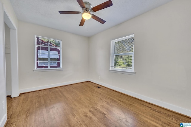 spare room featuring ceiling fan, a healthy amount of sunlight, light hardwood / wood-style floors, and a textured ceiling