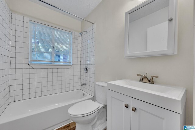 full bathroom featuring tiled shower / bath combo, a textured ceiling, toilet, vanity, and hardwood / wood-style flooring