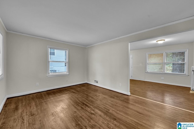 unfurnished room featuring dark wood-type flooring, plenty of natural light, and ornamental molding