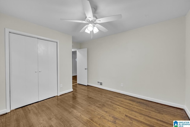 unfurnished bedroom with wood-type flooring, a closet, and ceiling fan