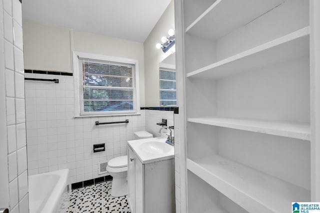 bathroom featuring vanity, toilet, tile walls, and a tub