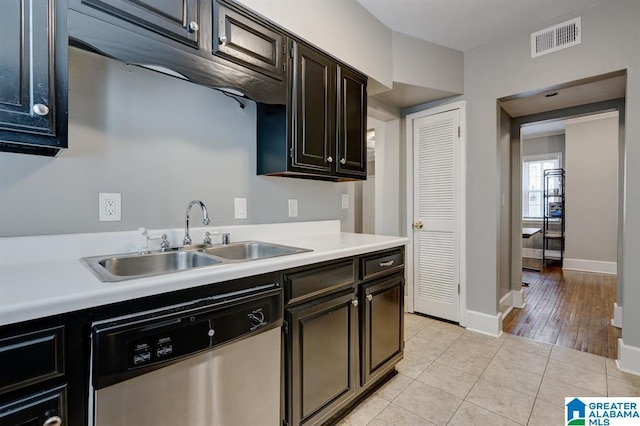 kitchen featuring dishwasher, light tile patterned floors, dark brown cabinets, and sink