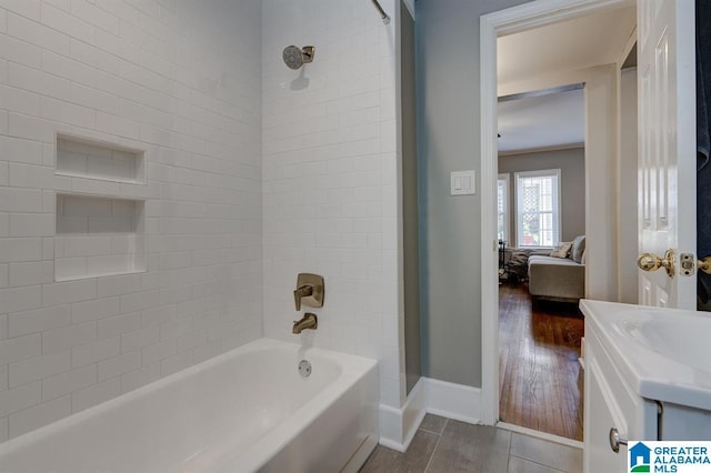 bathroom with hardwood / wood-style flooring, vanity, and tiled shower / bath