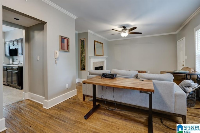 living room featuring hardwood / wood-style flooring, ceiling fan, ornamental molding, and sink