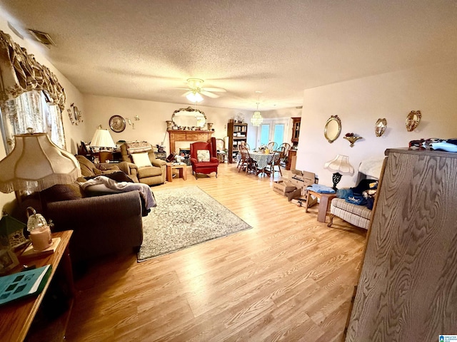 living room with hardwood / wood-style floors, a textured ceiling, and ceiling fan