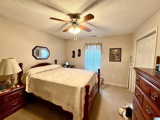 carpeted bedroom featuring ceiling fan, a textured ceiling, and a closet