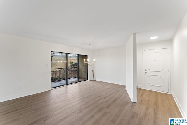 empty room with a chandelier and light hardwood / wood-style floors