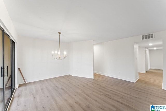 empty room featuring light hardwood / wood-style flooring and a chandelier