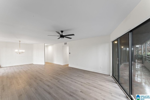 spare room featuring ceiling fan with notable chandelier and light wood-type flooring