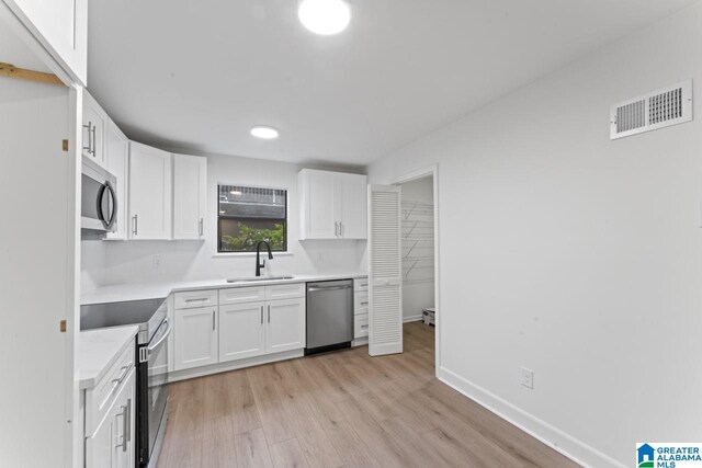 kitchen featuring sink, white cabinets, stainless steel appliances, and light hardwood / wood-style flooring