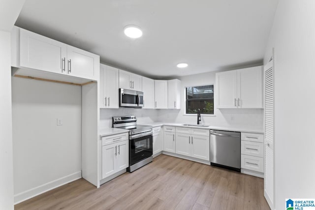 kitchen with backsplash, stainless steel appliances, sink, light hardwood / wood-style flooring, and white cabinets