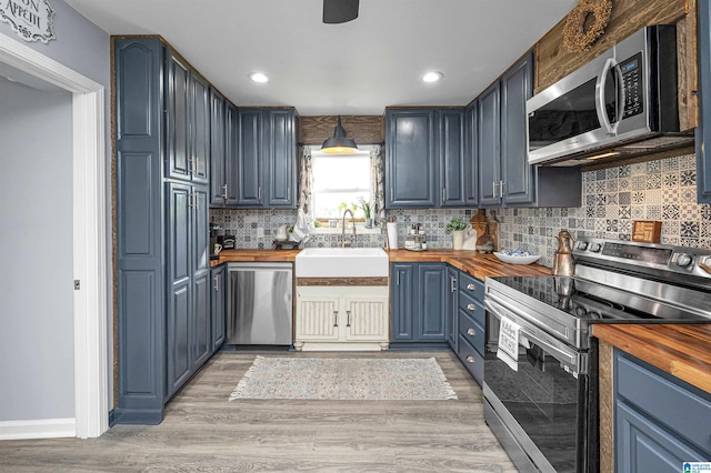 kitchen featuring stainless steel appliances, sink, wooden counters, and blue cabinets