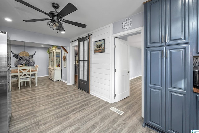 kitchen featuring blue cabinetry, hardwood / wood-style floors, a barn door, and ceiling fan