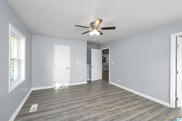 unfurnished bedroom featuring multiple windows, ceiling fan, and dark wood-type flooring