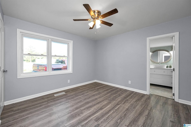 unfurnished bedroom with connected bathroom, ceiling fan, and dark wood-type flooring