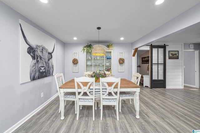 dining space featuring a barn door and wood-type flooring