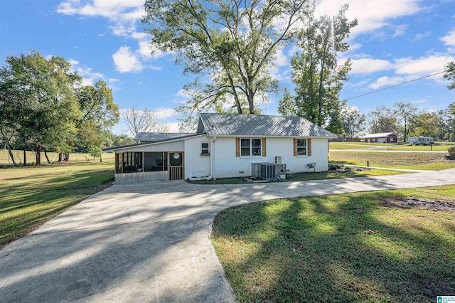 view of front of home with a sunroom, cooling unit, and a front yard