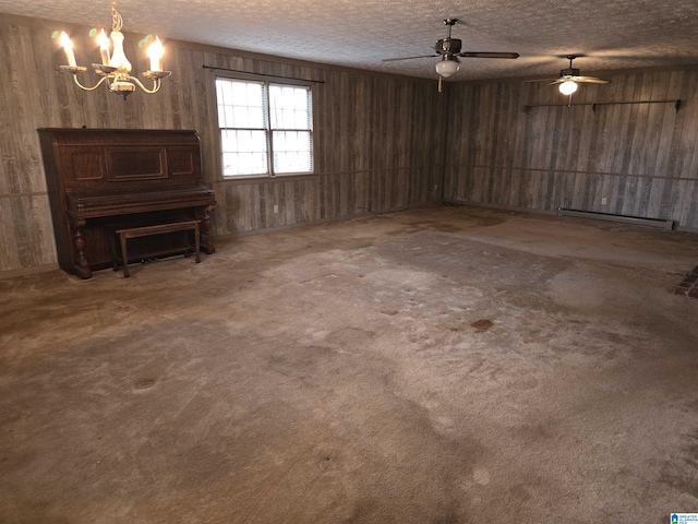 basement with wood walls, ceiling fan with notable chandelier, carpet flooring, a textured ceiling, and a baseboard radiator