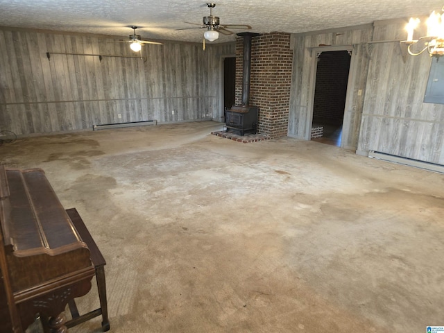 basement with a textured ceiling, a wood stove, and a baseboard heating unit