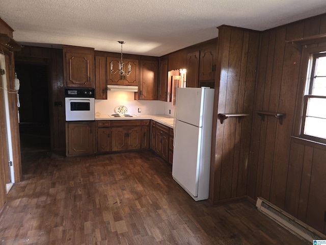 kitchen featuring white appliances, dark hardwood / wood-style floors, a textured ceiling, a baseboard radiator, and decorative light fixtures