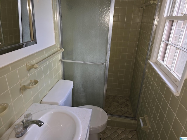 bathroom with vanity, tile patterned flooring, toilet, tile walls, and a shower with shower door