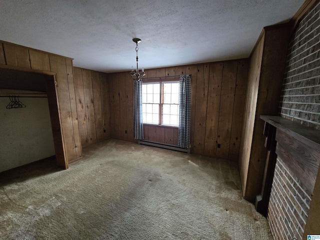 unfurnished dining area with a textured ceiling, wood walls, a notable chandelier, and a baseboard heating unit