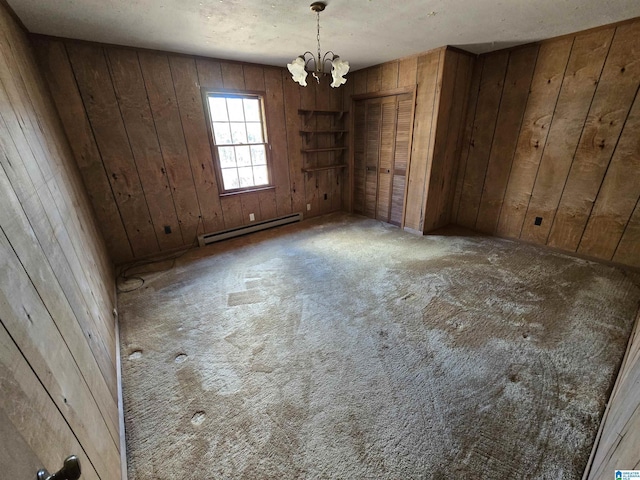 empty room featuring light colored carpet, baseboard heating, a notable chandelier, and wood walls