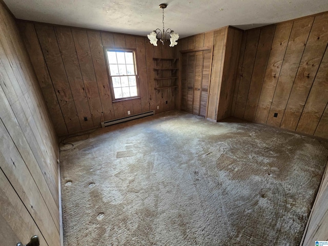 empty room with wooden walls, baseboard heating, and a notable chandelier