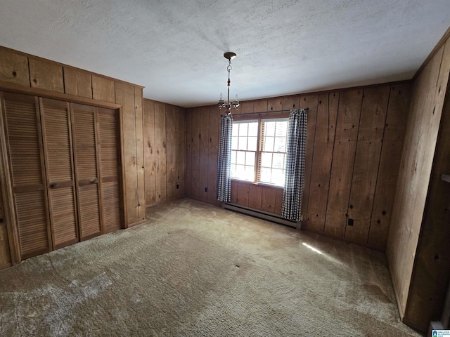 interior space featuring carpet floors, a baseboard radiator, wooden walls, and a notable chandelier