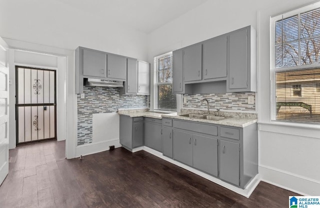 kitchen featuring backsplash, dark wood-type flooring, gray cabinetry, and sink