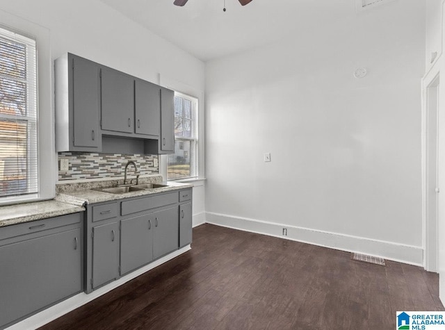 kitchen featuring backsplash, gray cabinetry, ceiling fan, sink, and dark hardwood / wood-style floors