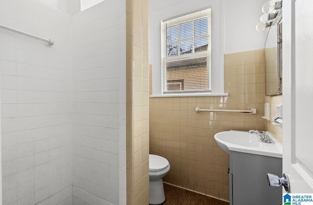 bathroom featuring vanity, tile walls, and toilet