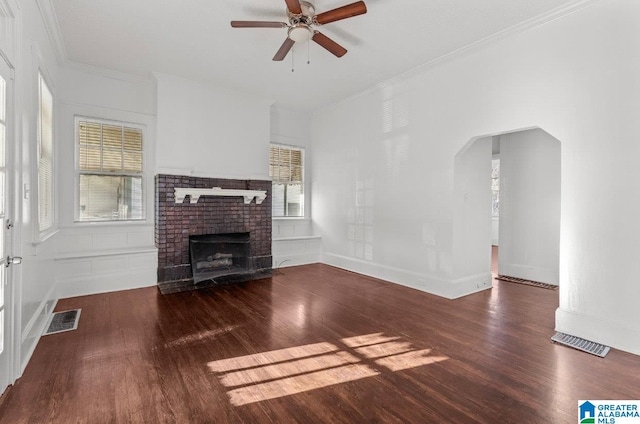 unfurnished living room with dark hardwood / wood-style flooring, a brick fireplace, ceiling fan, and crown molding