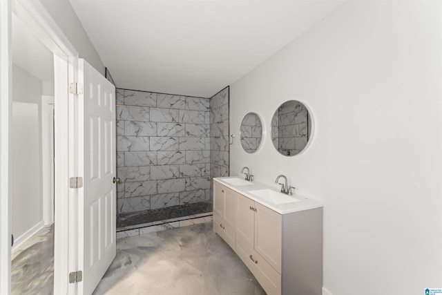 bathroom with concrete flooring, a tile shower, and vanity