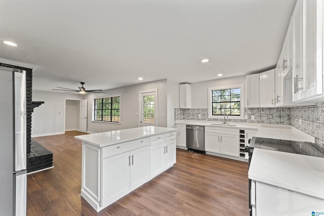 kitchen with stainless steel dishwasher, a center island, white cabinetry, and a brick fireplace