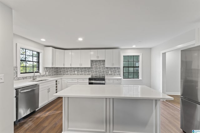 kitchen featuring appliances with stainless steel finishes, white cabinetry, a kitchen island, and sink