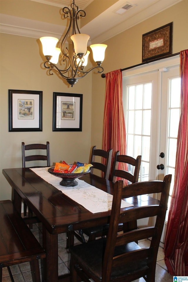 dining area with ornamental molding, an inviting chandelier, and french doors