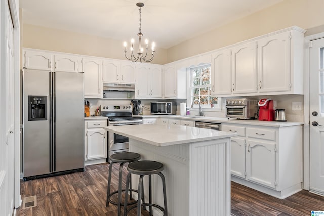 kitchen with a center island, white cabinets, appliances with stainless steel finishes, dark hardwood / wood-style flooring, and a chandelier