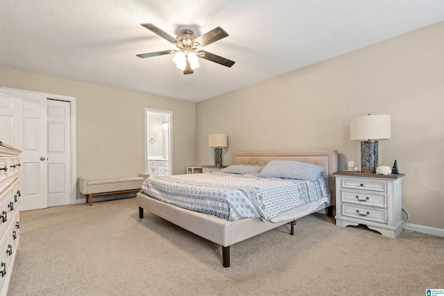 bedroom with ceiling fan, ensuite bathroom, and light carpet