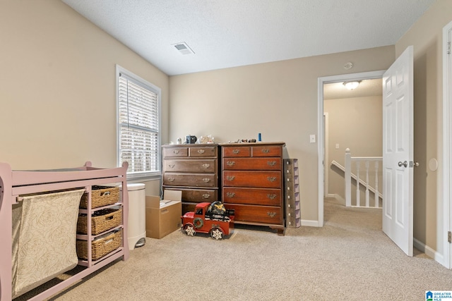 bedroom featuring light colored carpet and a textured ceiling