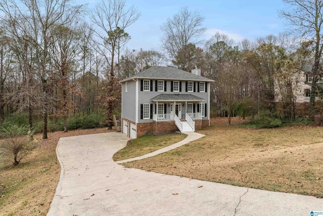 view of front of home with covered porch, a front yard, and a garage