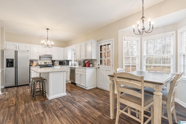 kitchen featuring a center island, white cabinets, hanging light fixtures, stainless steel appliances, and a chandelier