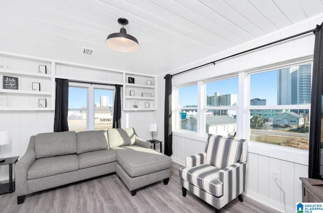 living room with built in shelves, wood ceiling, and hardwood / wood-style flooring