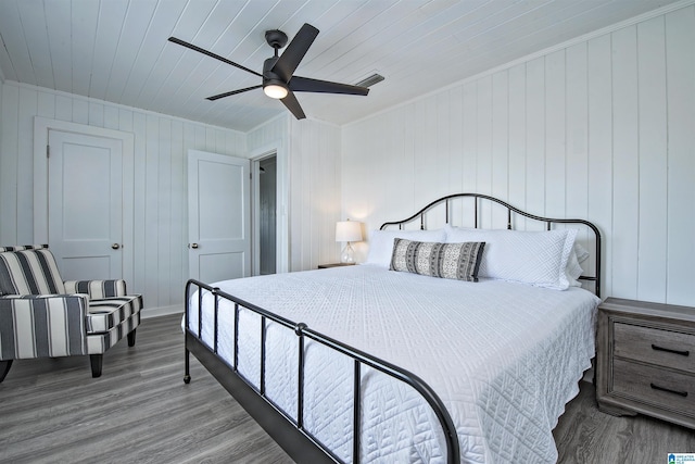 bedroom featuring ceiling fan, hardwood / wood-style floors, wood ceiling, and wood walls