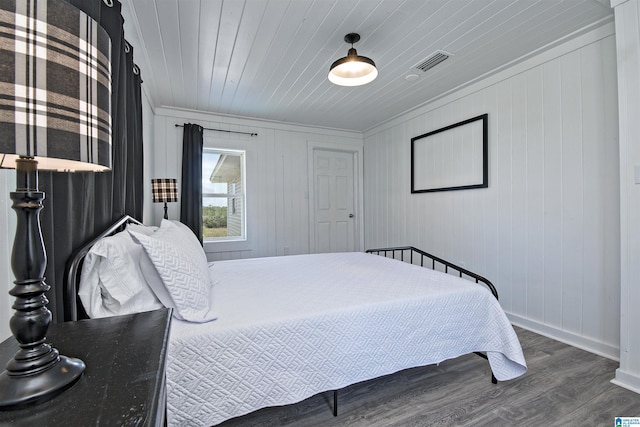 bedroom with wood walls, ornamental molding, dark wood-type flooring, and wood ceiling